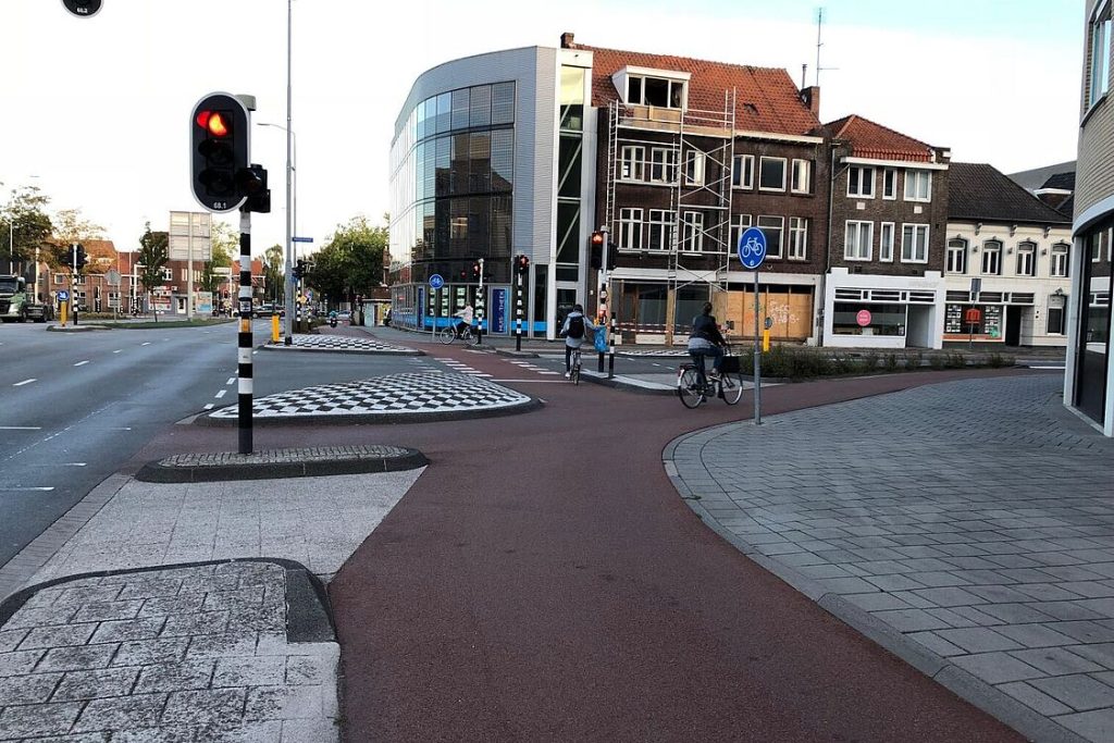 Das Bild zeigt die Radwegführung im Bereich einer Straßeneinmündung. Die Kurvenbereiche sind mit einer Erhöhung gegen Überfahren gesichert, der Radweg quert die Fahrbahn etwas zurückversetzt.